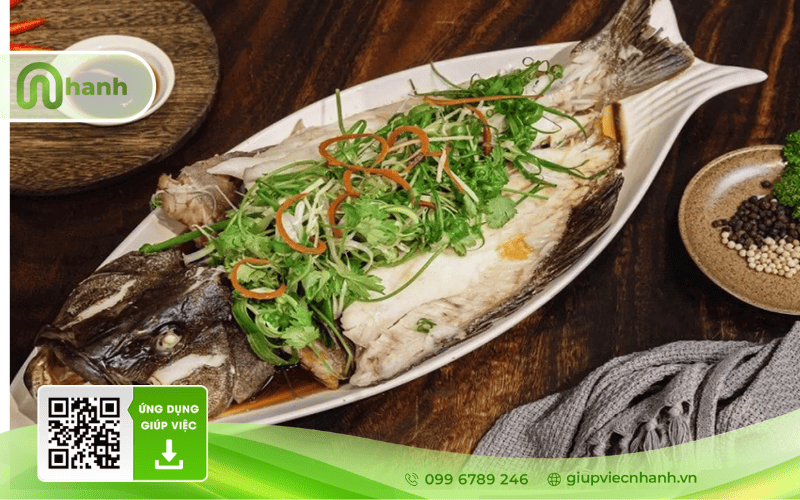 Món cá chẽm hấp xì dầu trình bày đẹp mắt với hành lá, ớt và ngò rí trên đĩa dài.